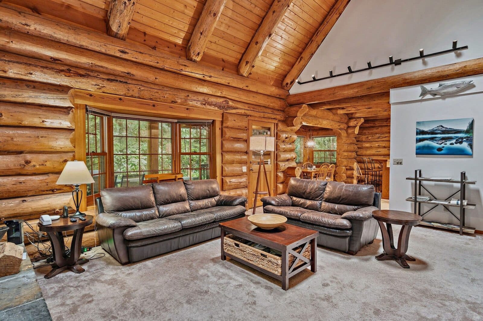 Listing photo: a cabin living room with sofas and a coffee table under exposed log beams