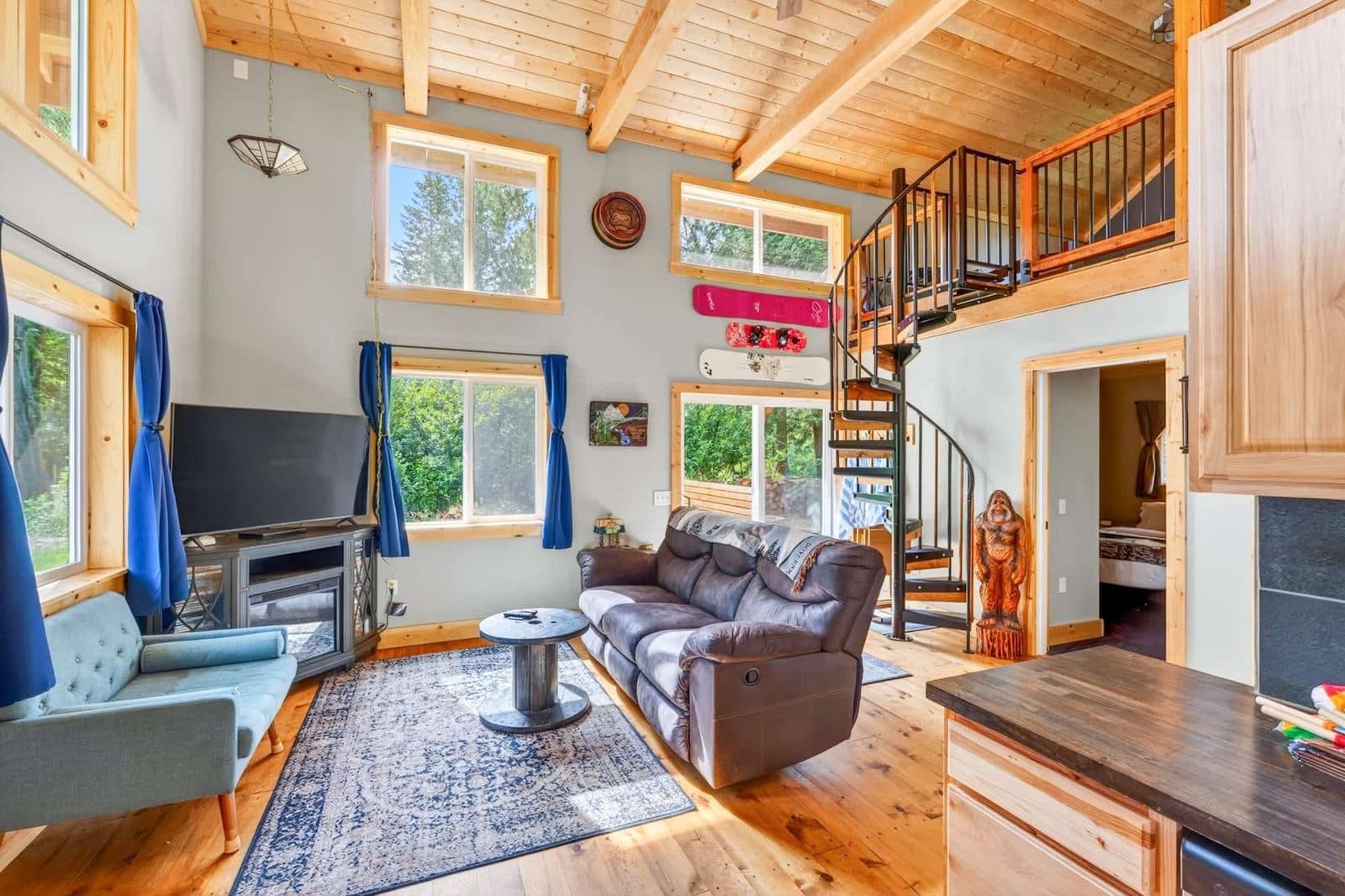 Listing photo: inside the Sandy cabin, a tall living room with a spiral stair up to the loft